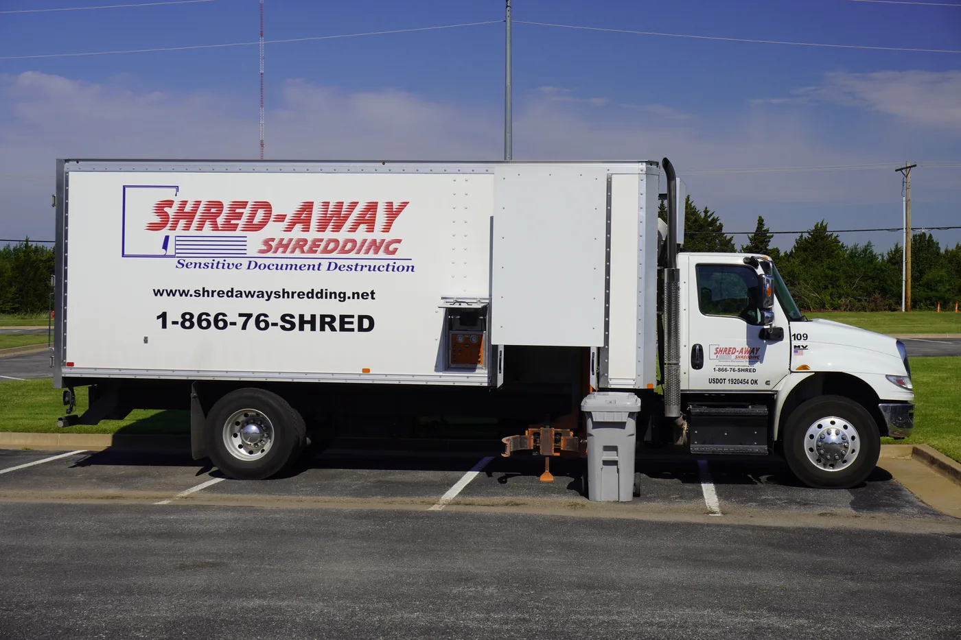 A Shred-Away truck parked at a customer lot with a locking bin at the lift.