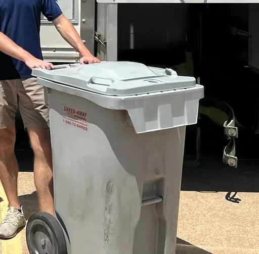 A Shred-Away locking bin being wheeled to the truck.