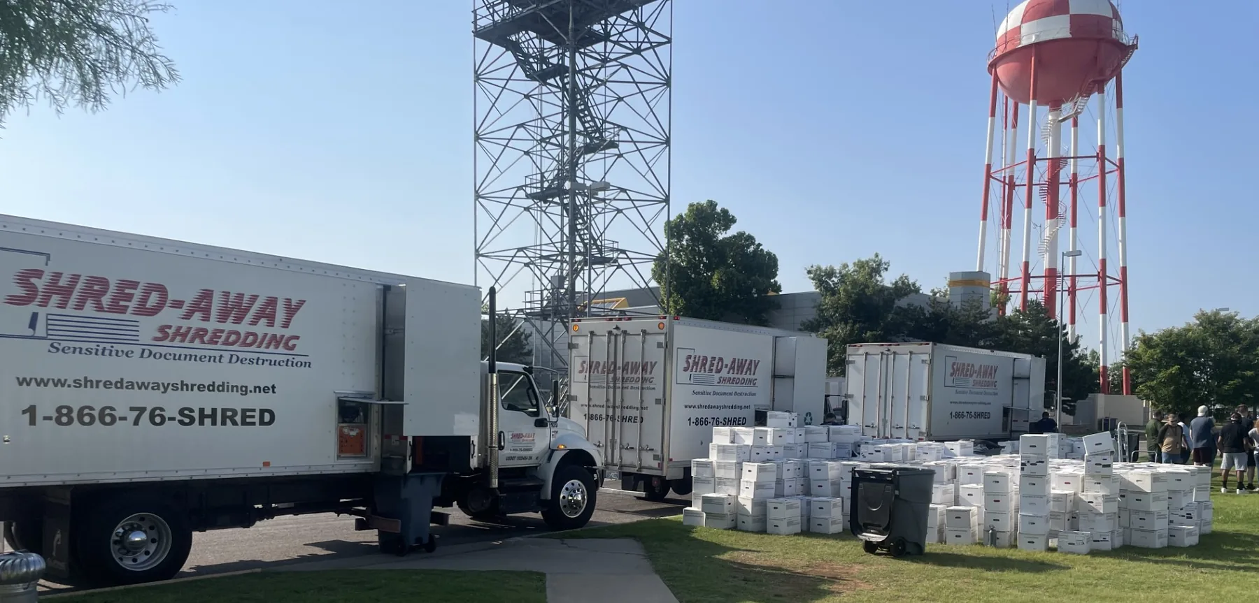 Four Shred-Away trucks lined up beside hundreds of file boxes at a large purge job.