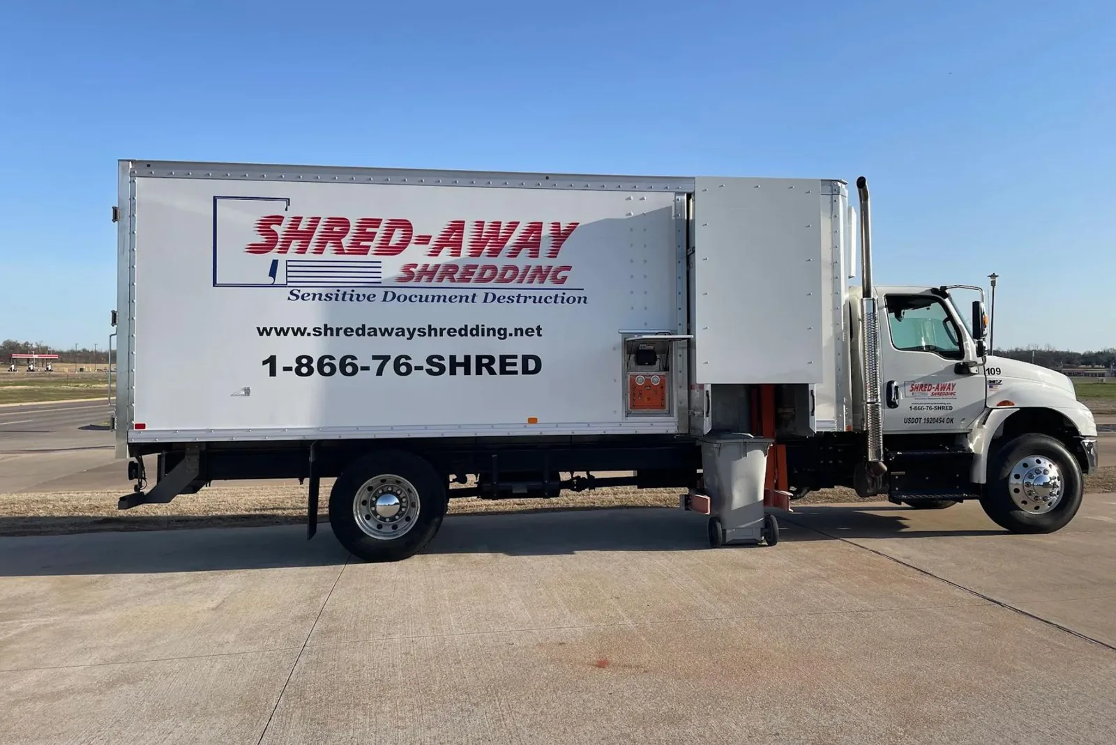A Shred-Away truck side-on with a locking bin at the lift.