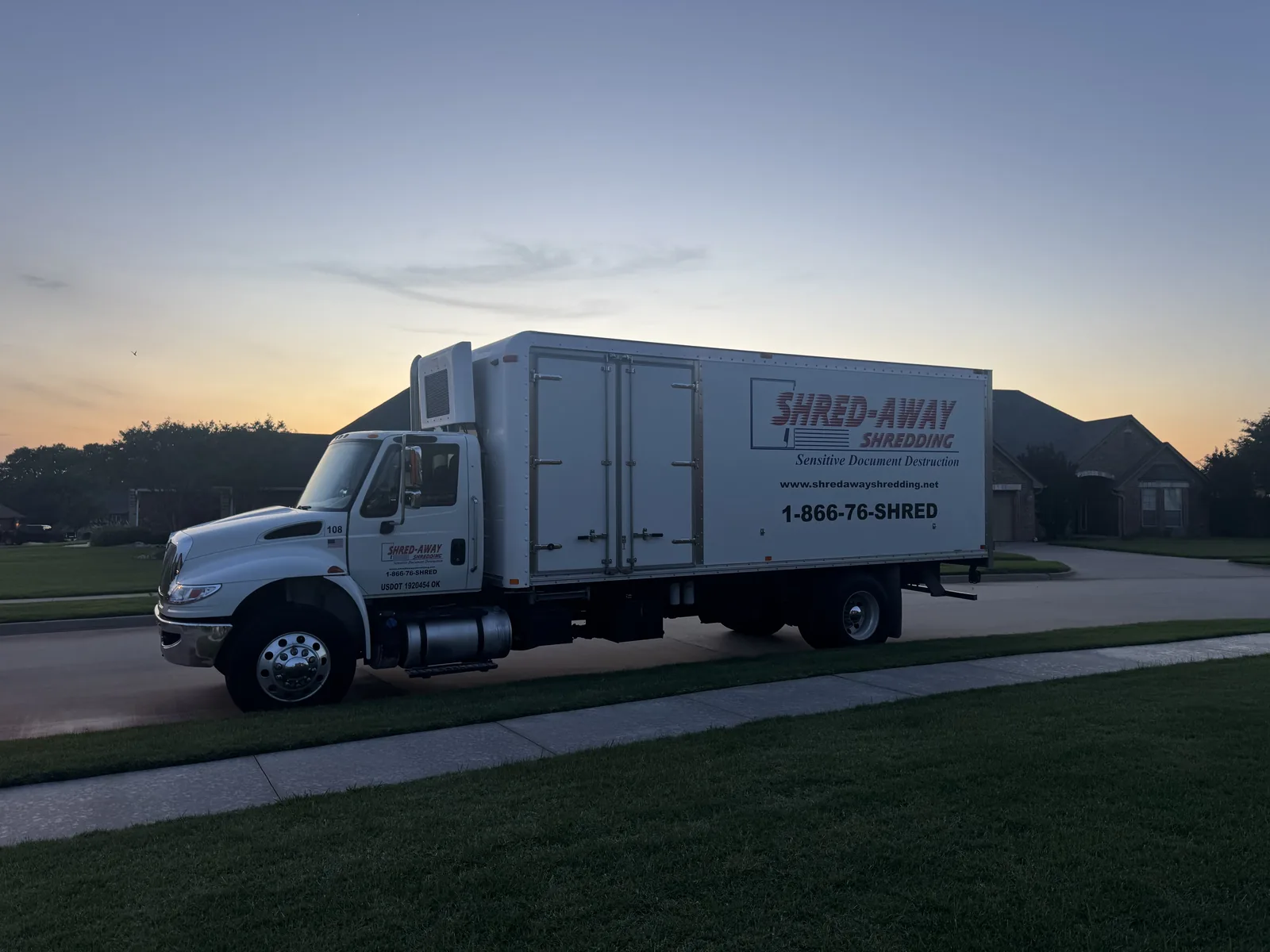 A Shred-Away shredding truck on the road at dusk.